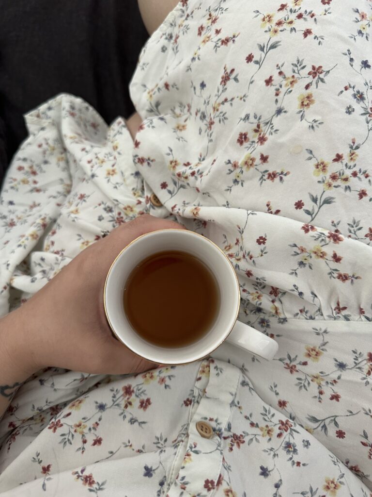 Mug of Chamomile tea woman holding while siting in floral dress